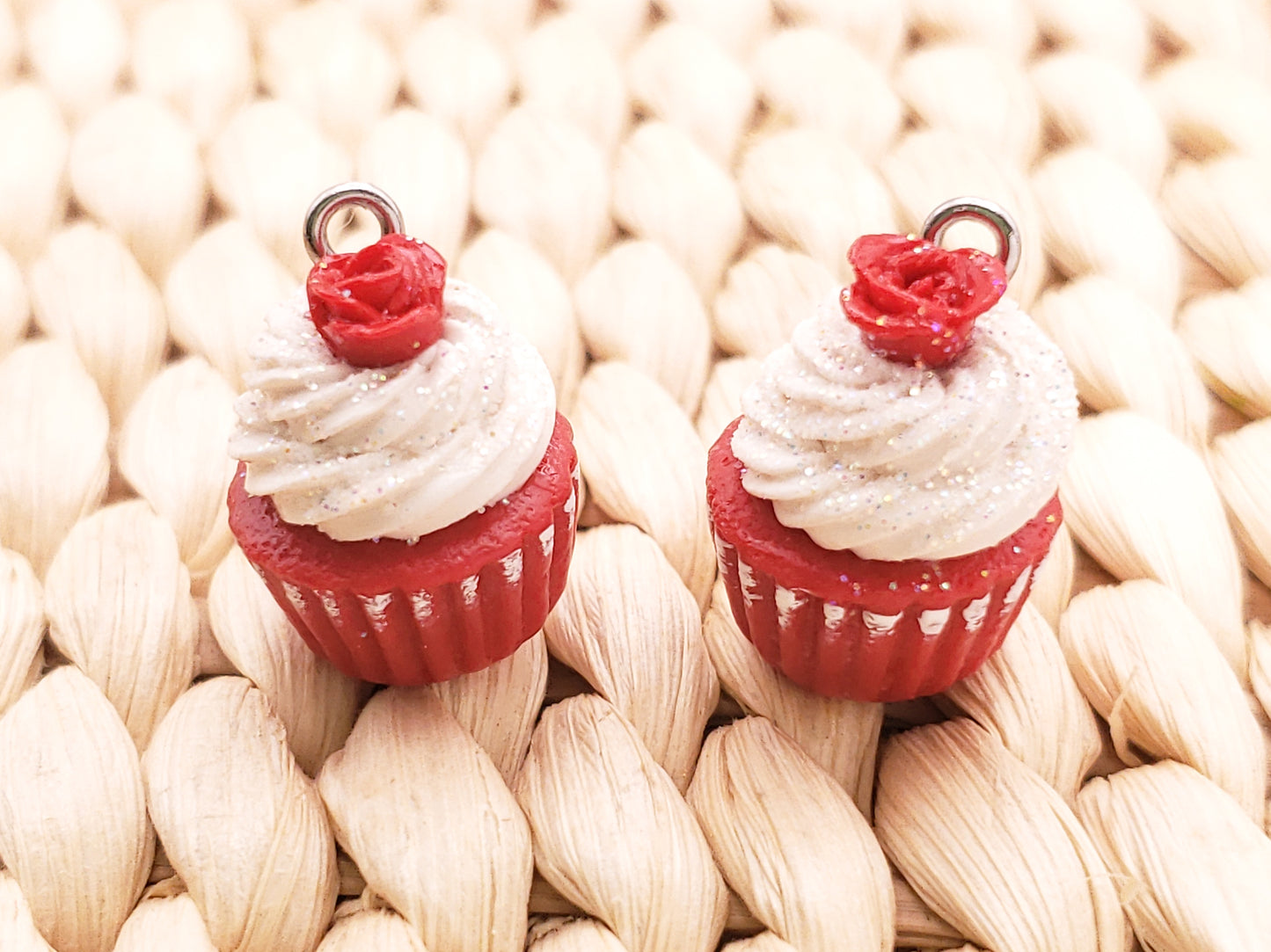 two cupcakes with white frosting and red bows