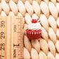 a red cupcake with white frosting sitting on a wooden ruler